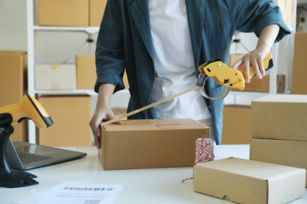 Young woman packing product in box for online order.
