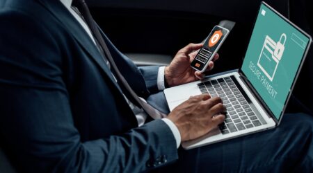 cropped view of african american businessman using laptop and smartphone in car with cyber security